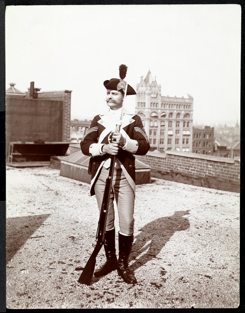 1895年にライフルを持った伝統的な軍服を着た屋上にいる男（銀ゼラチンプリント） 作： バイロンカンパニー
