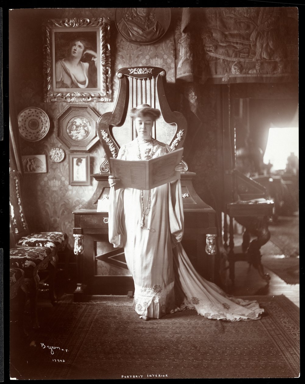開いた本を持って立っているIMクラーク夫人の肖像1904（銀ゼラチンプリント） 作： バイロンカンパニー