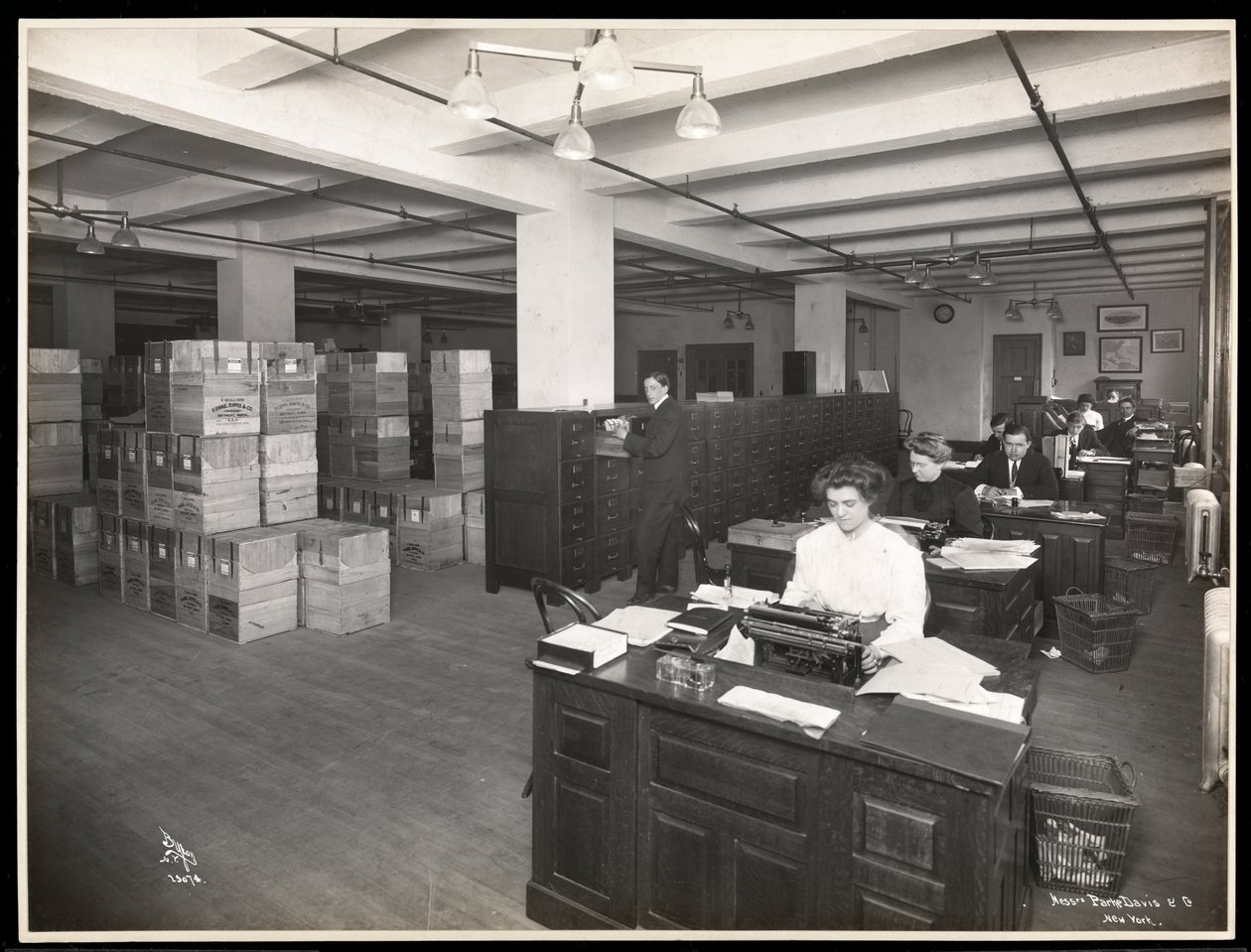 1910年にニューヨークのハドソンウントヴェストリーストリートにあるパークス、デービスウント社、化学者の発送室のように見えるデスクの男性と女性の様子（シルバーゼラチンプリント） 作： バイロンカンパニー