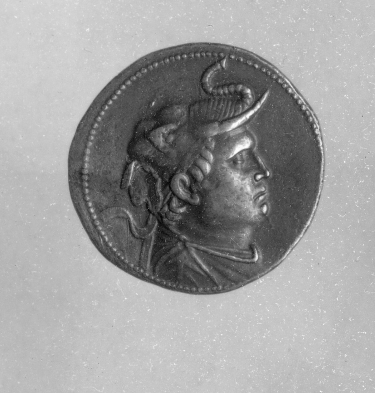 プトレマイオス1世（367BC- 283BC）によって造られたコイン。象の帽子と雄羊の角（銀色）を身に着けているアレクサンダー大王（356BC- 323BC）を示している。 作： エジプト人