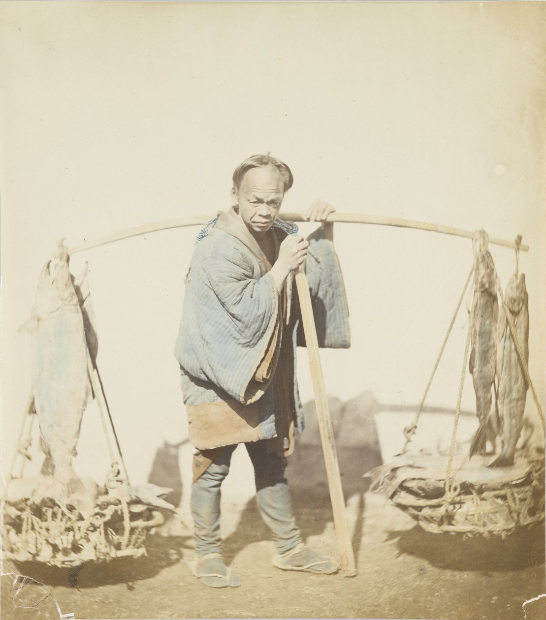 釣った魚を持つ漁師（手彩色のモノクロ写真 作： 日本の写真家