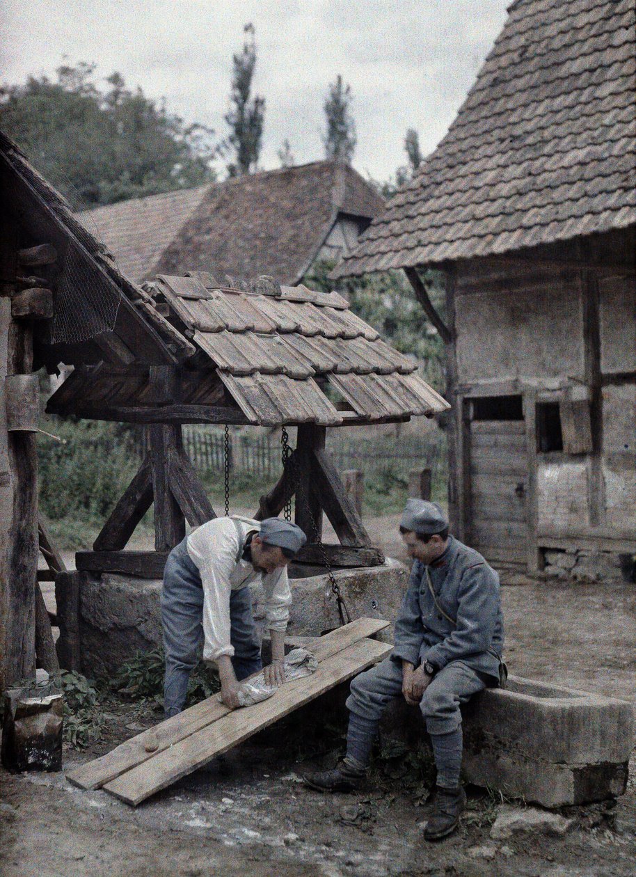 フランスの2人の兵士が1917年6月21日、フランス、アルザス地方、オートラン県ギルドヴィレールの町の農家近くの噴水の谷に設置されたボードを使って洗濯物を世話している（a 作： ポール・カステルナウ