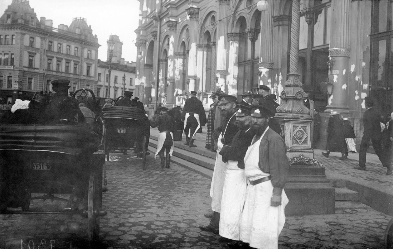 1913年、サンクトペテルブルクのネフスキー大通り、ニコラス駅の外にいるポーターと乗客 作： ロシアの写真家