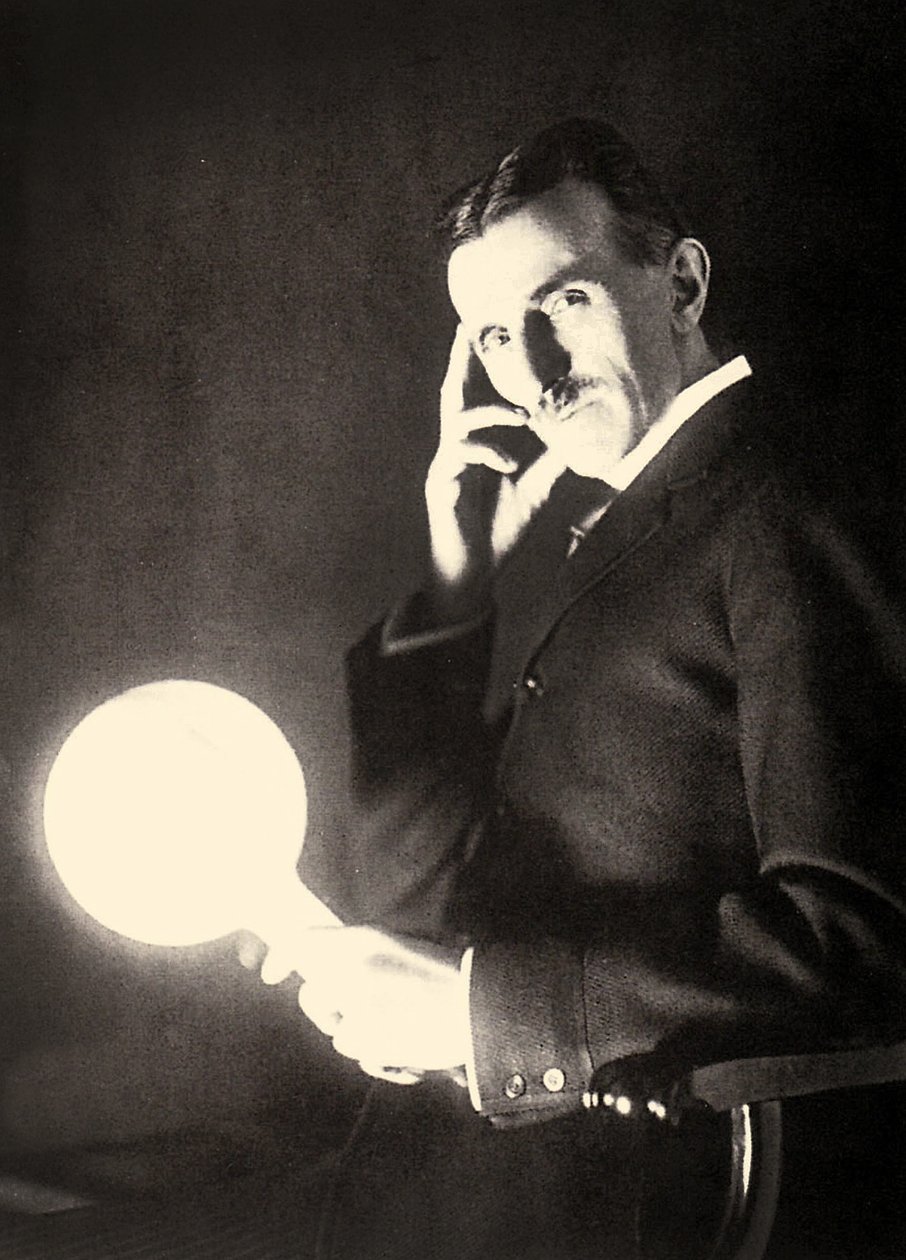 テスラコイルの電磁界に照らされた電球を保持しているニコラテスラの肖像画、1899年 作： 不明不明